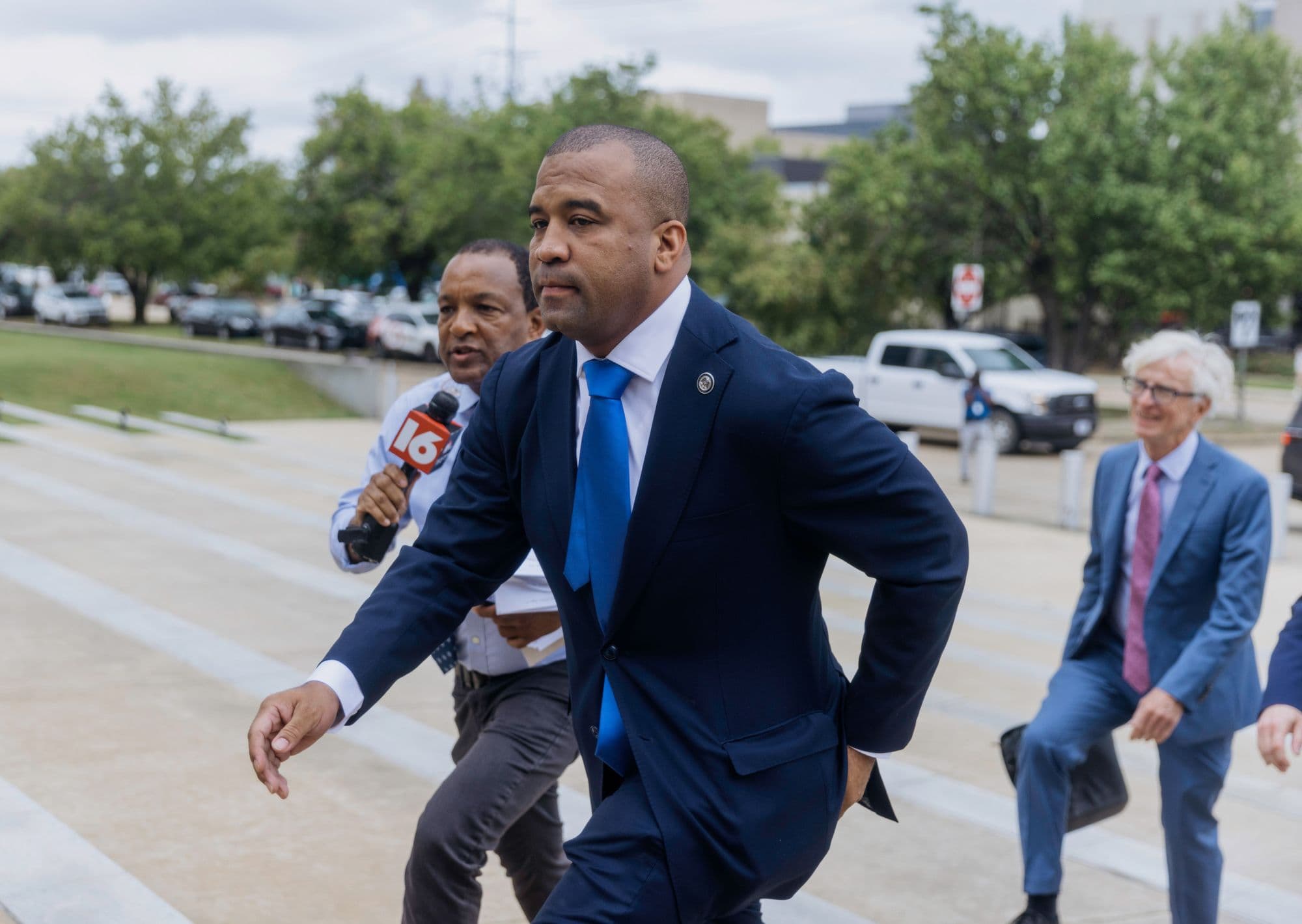 Hinds County District Attorney Jody Owens arrives at the federal courthouse as a reporter follows with a microphone.