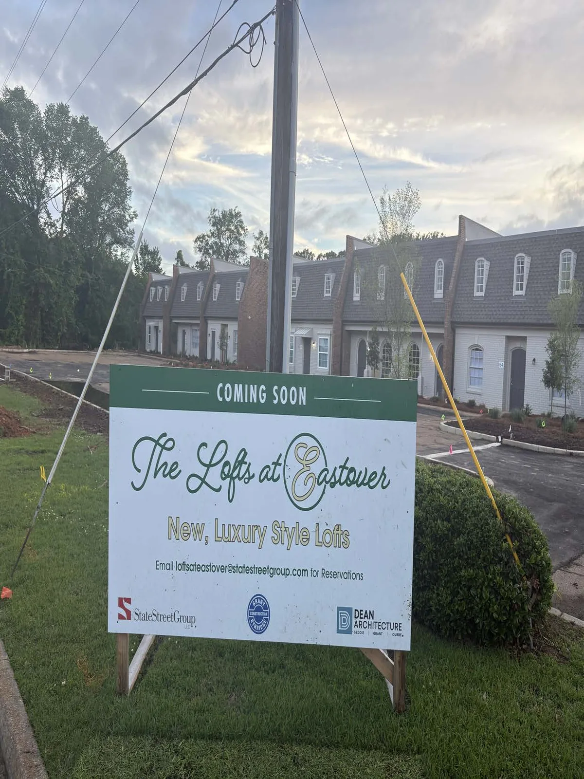 A green-and-white “Coming Soon — The Lofts at Eastover” sign on the lawn at 2625 Ridgewood Road, with the converted townhouse-style building behind it.
